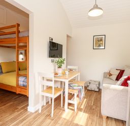 A small living area with a bunk bed sleeping nook dining table with chairs and a sofa at Bramble in Banham