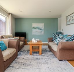 A living room with brown sofas a wooden coffee table and paintings on the walls at Lodge Sixty Six in St Columb Major