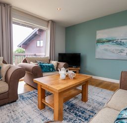 A living room with armchairs cushions wooden coffee table and a television at Lodge Sixty Six in St Columb Major
