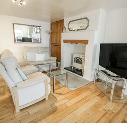 A living room with a sofa, coffee table, and television at Preswylfa Apartment in Caernarfon