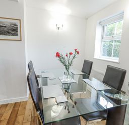 A dining room with a glass table and chairs at Preswylfa Apartment in Caernarfon