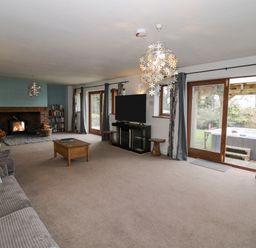 A living room with a fireplace a TV a coffee table and sliding glass doors leading outside at Shatterford Lakes in Shatterford
