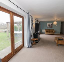 A living room with sofas a coffee table a television and glass doors leading to a garden at Shatterford Lakes in Shatterford