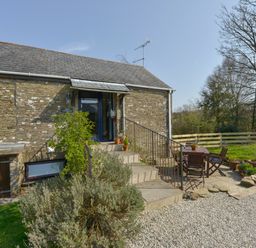 A stone cottage entrance with stairs and outdoor table and chairs in a garden at Erin Cottage in Pelynt near Looe