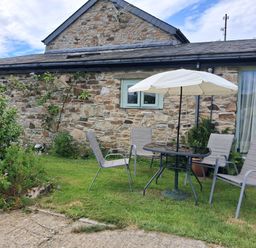 A garden with a table and chairs at Owl Barn in Tavistock