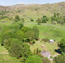 A house surrounded by trees and fields with hills in the background at Cae Lleci Llanfachreth near Dolgellau