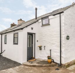 The exterior of a white cottage with a gray door and windows a potted plant and a small concrete step at Laal Riddings Lowick Green Riddings Farm Near Ulverston