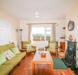A living room with green armchairs sofa wooden coffee table and fireplace at The Trawler in Blackwater County Wexford
