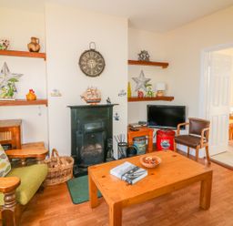 A living room with a green armchair wooden coffee table and fireplace at The Trawler in Blackwater County Wexford