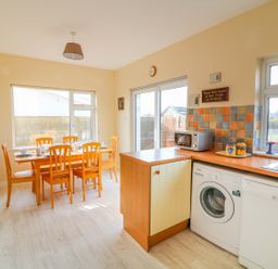 A kitchen and dining area with wooden chairs around a table and appliances by the counter at The Trawler in Blackwater County Wexford
