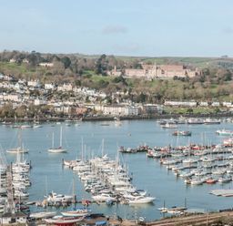 A marina with boats and yachts on the water with houses and hills in the background at Moorings in Kingswear Devon