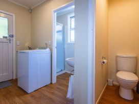 A bathroom with a washing machine, toilet, sink and shower at Kune Crib - Ohakune Holiday Home near Turoa