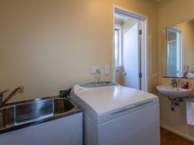 A laundry room with a washing machine and sink at Kune Crib - Ohakune Holiday Home near Turoa