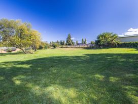 A grassy area with trees and a fence at Kune Crib - Ohakune Holiday Home near Turoa