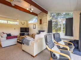 A living room with a sofa, armchairs, and a television at Kune Crib - Ohakune Holiday Home near Turoa in Ohakune