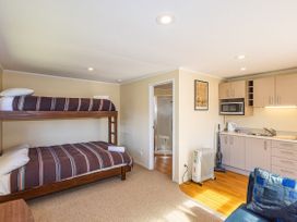 A bedroom with a bunk bed and kitchenette at Kune Crib - Ohakune Holiday Home near Turoa