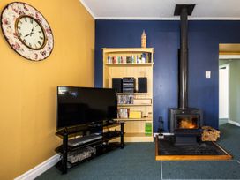 A living room with a television and wood stove at Oroua Cottage - Rangataua Bach Ohakune
