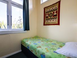 A bedroom with a bed and a wall hanging at Oroua Cottage - Rangataua Bach Ohakune