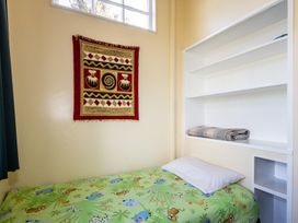 A bedroom with a bed and shelf at Oroua Cottage - Rangataua Bach Ohakune