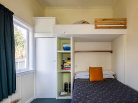 A bedroom with a bed and shelves at Oroua Cottage - Rangataua Bach Ohakune