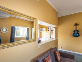 A living room with a mirror and sofa at Oroua Cottage - Rangataua Bach Ohakune