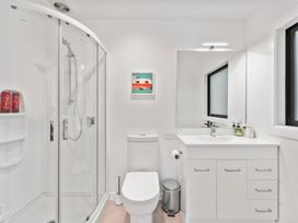 A bathroom with a shower, toilet, sink and mirror at Pukawa Haven - Pukawa Bay