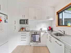 A kitchen with cabinet, oven, microwave, kettle, and sink at Pukawa Haven - Pukawa Bay