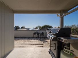 An outdoor patio with a barbecue grill and chairs at Joes Place - Cooks Beach