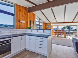 A kitchen with a window and dining area at Joes Place - Cooks Beach Holiday Home