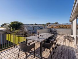 An outdoor deck with a table and chairs at Joes Place - Cooks Beach Holiday Home Cooks Beach
