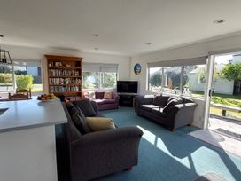 A living room with furniture and a television at Silver Sands - Cooks Beach Holiday Home Cooks Beach