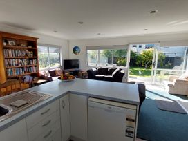 A living room with a bookshelf and sofa at Silver Sands - Cooks Beach Holiday Home in Cooks Beach