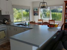A kitchen with a sink and dining table at Silver Sands - Cooks Beach Holiday Home Cooks Beach