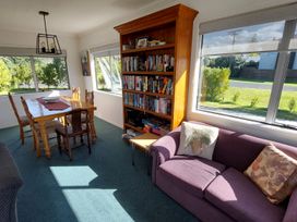 A living room with a bookshelf and dining table at Silver Sands - Cooks Beach Holiday Home in Cooks Beach
