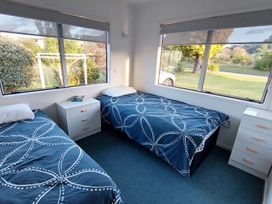 A bedroom with two beds and a nightstand at Silver Sands - Cooks Beach Holiday Home Cooks Beach