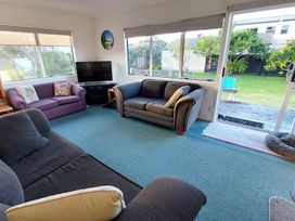 A living room with sofas and a television at Silver Sands - Cooks Beach Holiday Home Cooks Beach