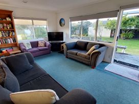 A living room with a bookshelf and television at Silver Sands - Cooks Beach Holiday Home Cooks Beach