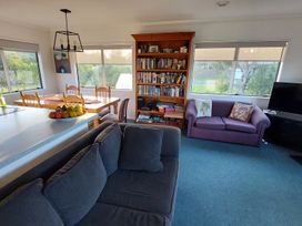 A living room with a couch and dining table at Silver Sands - Cooks Beach Holiday Home Cooks Beach