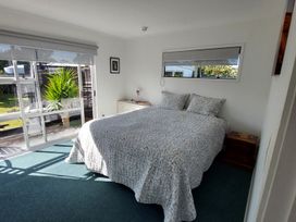 A bedroom with a bed and a large window at Silver Sands - Cooks Beach Holiday Home Cooks Beach