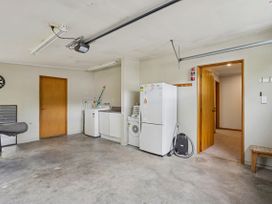 A laundry room with appliances and a dartboard at Tranquil Tipperary - Arrowtown Holiday Home