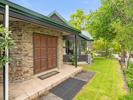 A front yard of a house with a stone wall and wooden door at Tranquil Tipperary - Arrowtown Holiday Home in Arrowtown