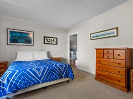 A bedroom with a bed and dresser at Beach Galore - Waihi Beach Holiday Home
