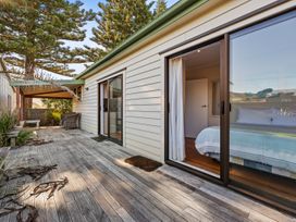 An outdoor area with a wooden deck and seating at Beach Galore - Waihi Beach