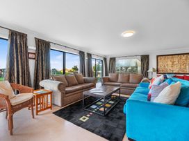 A living room with a sofa and armchair at Beach Galore - Waihi Beach Holiday Home, Waihi Beach