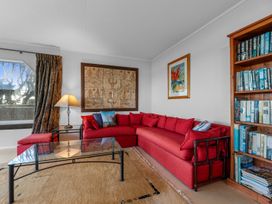 A living room with a red couch and bookshelf at Beach Galore - Waihi Beach Holiday Home