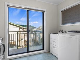 A laundry room with a washing machine and a sliding door at Beach Galore - Waihi Beach
