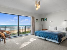 A bedroom with a bed and a view of the ocean at Beach Galore - Waihi Beach