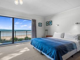 A bedroom with a bed and a view of the sea at Beach Galore - Waihi Beach
