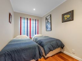 A bedroom with two beds and framed artwork at Beach Galore - Waihi Beach Holiday Home