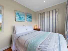A bedroom with a bed and lamp at Beach Galore - Waihi Beach Holiday Home